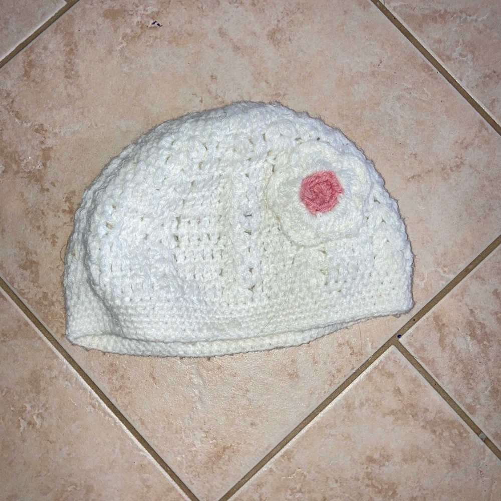 White knitted hat with pink flower detail.